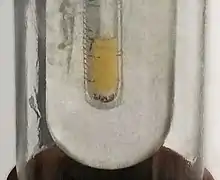 A glass tube, is inside a larger glass tube, has some clear yellow liquid in it
