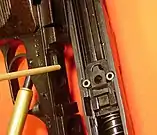 Roller locks in the CZ 52 pistol. When fired, slide and barrel move rearward but the locking piece in the slide is held by the tab indicated by the pointer.