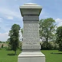 Boggs monument. Inscription reads "Capt. John Boggs born in western Penn. 1738. Married Jane Irwin and raised a large family on the frontier near Wheeling, W. Va. One son Wm. was taken prisoner by the Indians in view of his fathers cabin which is here represented. Another James was killed by them near Cambridge O. Emigrated to Ohio and built his cabin on this spot 1798 and died 1826."