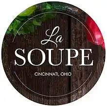 logo of La Soupe, a stylized wooden plate and partial images of produce, with the words "La Soupe" large and centered on the plate and "Cincinnati, Ohio" in block letters centered under the organization name