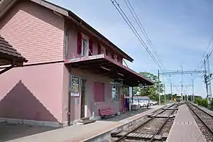 Two-story station building next to double-tracked railway line