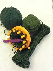 Fingerless gloves being knitted on a 12-peg frame