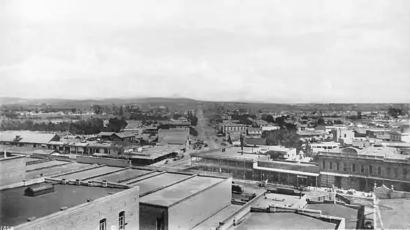 1885 view of the east side of Los Angeles St. with Bell Block at center with its two story porch, to its right Mellus Row, then Hellman, Haas & Co. At center is Aliso St. heading east (top center of photo).