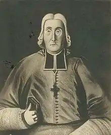 Black and white illustration of a man wearing liturgical vestments and a pectoral cross facing forward, with a book in his right hand and an ecclesiastical ring on his right ring finger.