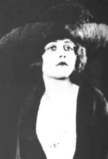 A young white woman wearing a large dark hat and a dark jacket or shawl