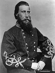 Black and white photo of a bearded man wearing a dark gray military uniform with frogging on the sleeves.