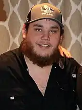 A bearded young man wearing a baseball cap and a dark shirt