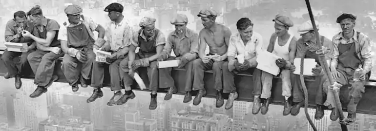 Close-up of the 11 men sitting on a steel beam.