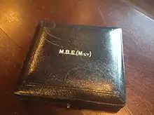 Square, blue leather case with gold lettering. MBE bracket Mily bracket