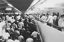 Picture of several people arriving to an already crowded platform.