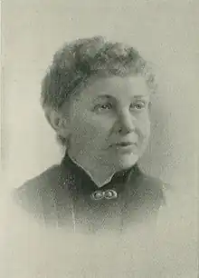 Portrait photograph of a middle-aged woman with her hair in an up-do, and wearing a high-collared blouse.