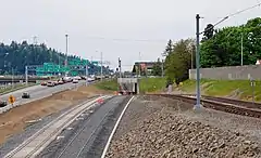 Photograph of the MAX Green Line under construction shows the underpass under Glisan Street and two new track lines—one completed. They are next to the Blue Line tracks at right in this photo. The exit ramp from northbound I-205 to Glisan Street is at the left.