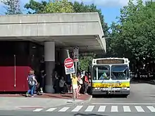 A city bus next to a headhouse for an underground train station
