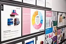 A close-up view of a packaging materials display featured at the MCX offices in New York City. A colorful graphic of industries and innovative materials are affixed to boards on the library wall.