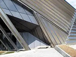 The entrance of the Eli and Edythe Broad Art Museum, highlighting the complex angles of the building and an enticing movement from the stunning stainless steel pleated exterior and layered concrete arches.
