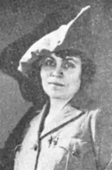 A white woman with dark hair, wearing military-style uniform and cap
