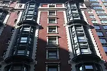 The facade of the annex on 29th Street. . On the second through eleventh stories, the central bay contains rectangular windows with slightly protruding frames, while the outer bays have curving metal windows, similar to in the original building.