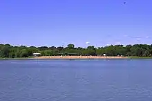 beach and trees viewed from across the lake