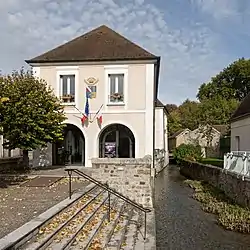 The town hall and river Orvanne in Voulx