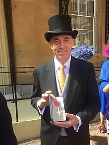 Dr Mann is holding the medal representing the receipt of an OBE
