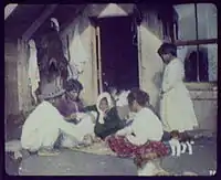 Maori woman and children playing cards on doorstep of their home in Whakarewarewa, 1895