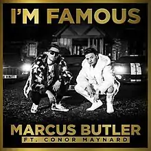 A greyscale photograph of Butler and Maynard crouching down in front of cars and a house. The photo has a gold border, and the song's title and the names of the artists are written in large gold lettering.
