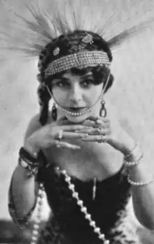 A white woman wearing a spiky headdress and pearls