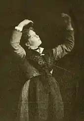 A standing woman with her bent arms rigidly raised