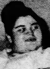 A newspaper photograph of a young white woman with dark hair in a top bun.