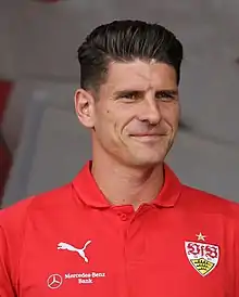 Gomez in a red Stuttgart shirt against a blurred white background