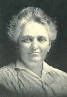 A middle-aged white woman with greying hair swept back from her face