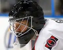 man wearing black goalie mask and hockey equipment