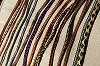 Several lengths of colourfully-woven braids on a cream background.