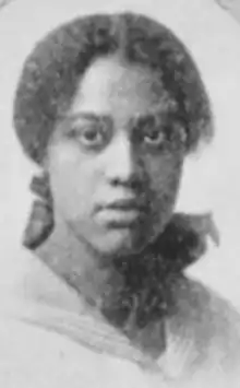 A young Black woman, hair parted center and dressed to nape, wearing a sailor-style collar