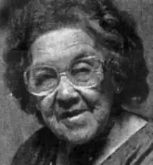 An older Native American woman with grey set hair, wearing glasses