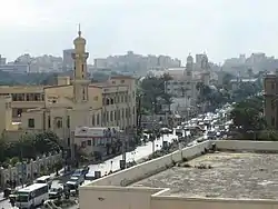A mosque and a church in Suez Canal Street, Al Shatby. The Alexandria Tram line is visible crossing the street.