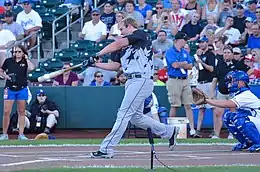 A man in a gray baseball jersey swinging a bat
