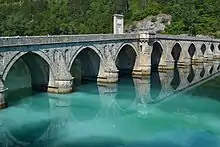 A bridge with many arcs across a river.