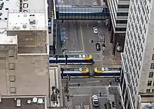 An aerial shot of two light rail trains traveling on 5th St past the Marq2 corridor.