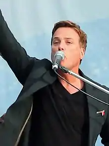 Michael W. Smith sings into the microphone with one hand in the air