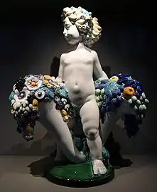 Secessionist putto with two cornucopias with floral cascades, flowers very similar to the ones found in a lot of Art Deco of the 1910s and 1920s, by Michael Powolny, designed in c. 1907, produced in 1912, ceramic, Kunstgewerbemuseum Berlin, Berlin, Germany