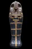Black and gold coffin lid shaped like a mummy