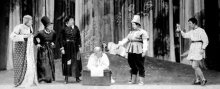 stage scene with six rustics in approximately Elizabethan costume