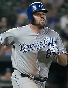 A man in a gray baseball uniform and blue batting helmet