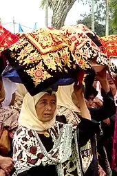 Minangkabau women carrying platters of food to a ceremony