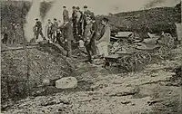 Miners with shovels and wheelbarrows working at an ore heap (ca. 1907)