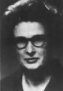 A middle-aged white woman with dark hair and glasses