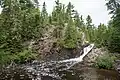 The Upper Falls of the Montreal River, showing the rugged shoreline and predominantly coniferous forest