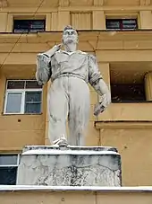 Statue of worker in front of tan apartment building