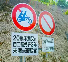 Regulation of motorcycle access on freeways: Japanese traffic signs near motorway entrance: – No pillion passenger for a driver under 20 or with less than 3 years experience (left) – Road closed for two-wheeled vehicles ≥125cc and heavy equipment (right)
